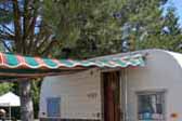 classic red, orange and green striped awning with scalloped edging on a 1960 Aloha 15ft vintage trailer